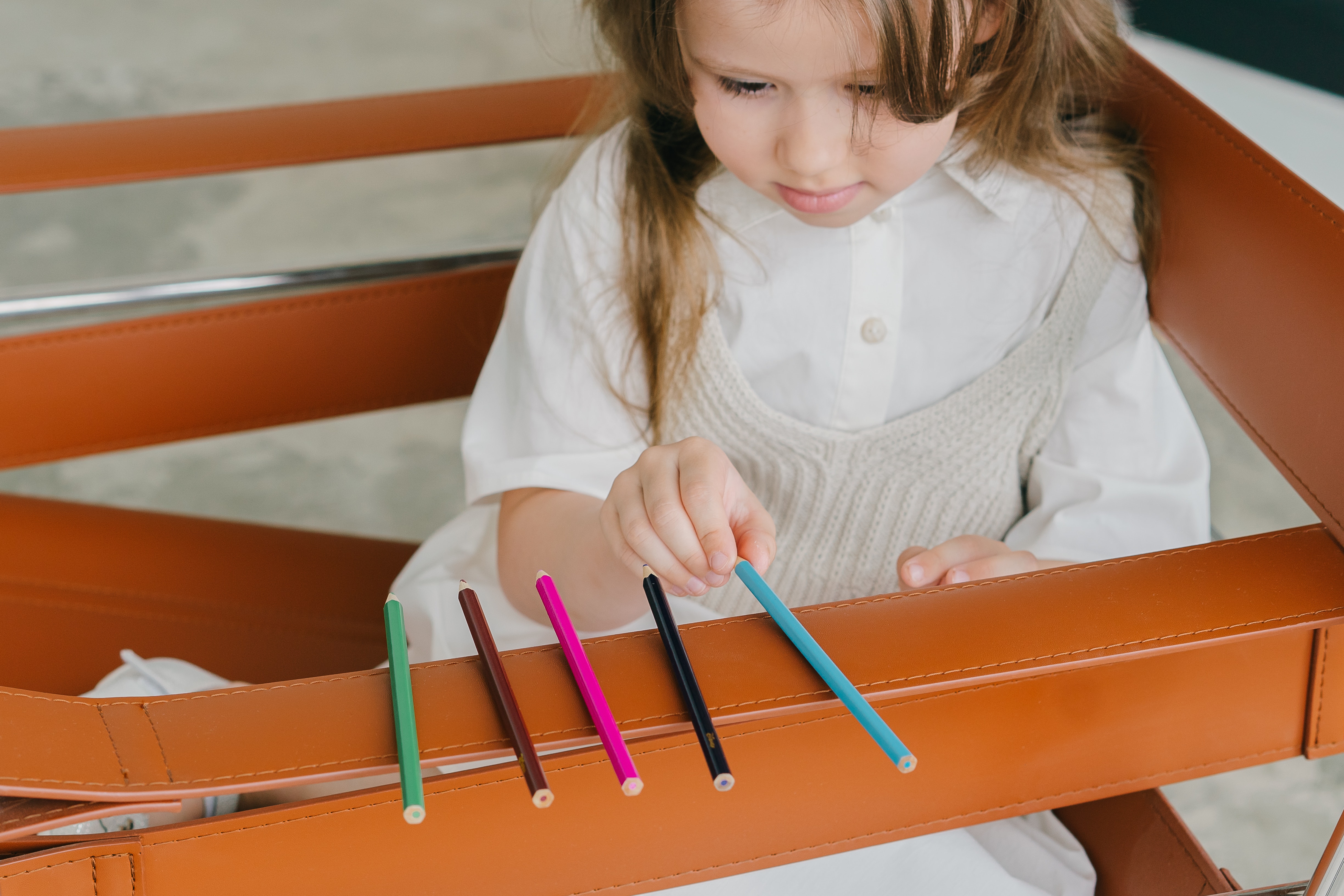 A child organising colouring pencils in a line 