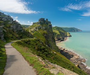 View of a dramatic coastline and cliffs, blue sea and skies with a single path