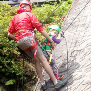 A young boy and a man abseiling together