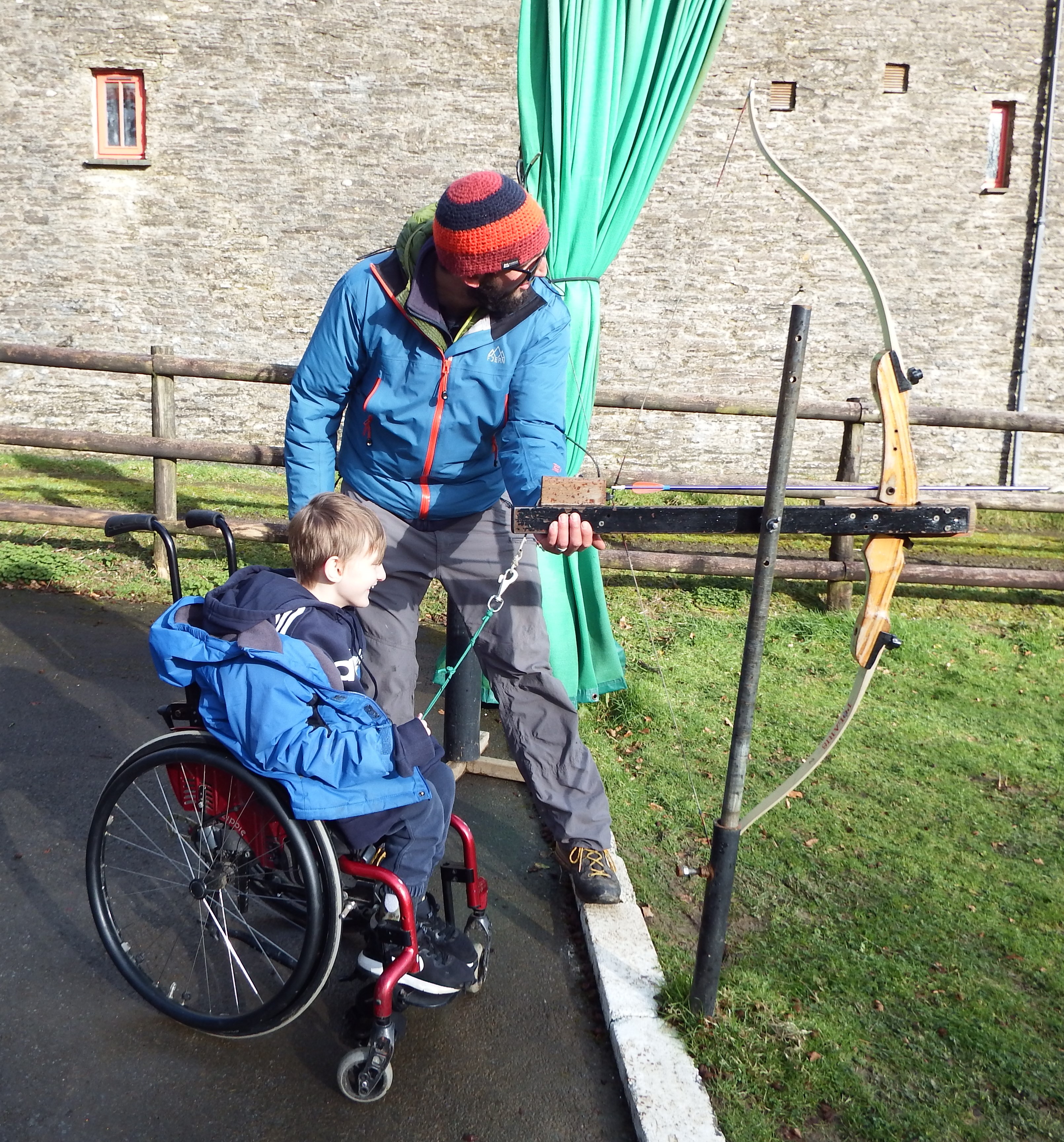 A young boy in a wheelchair trying archery with an adapted bow