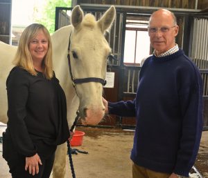 Jenny Young and Peter Maggs stood posing for the camera with a white Calvert Exmoor horse between them