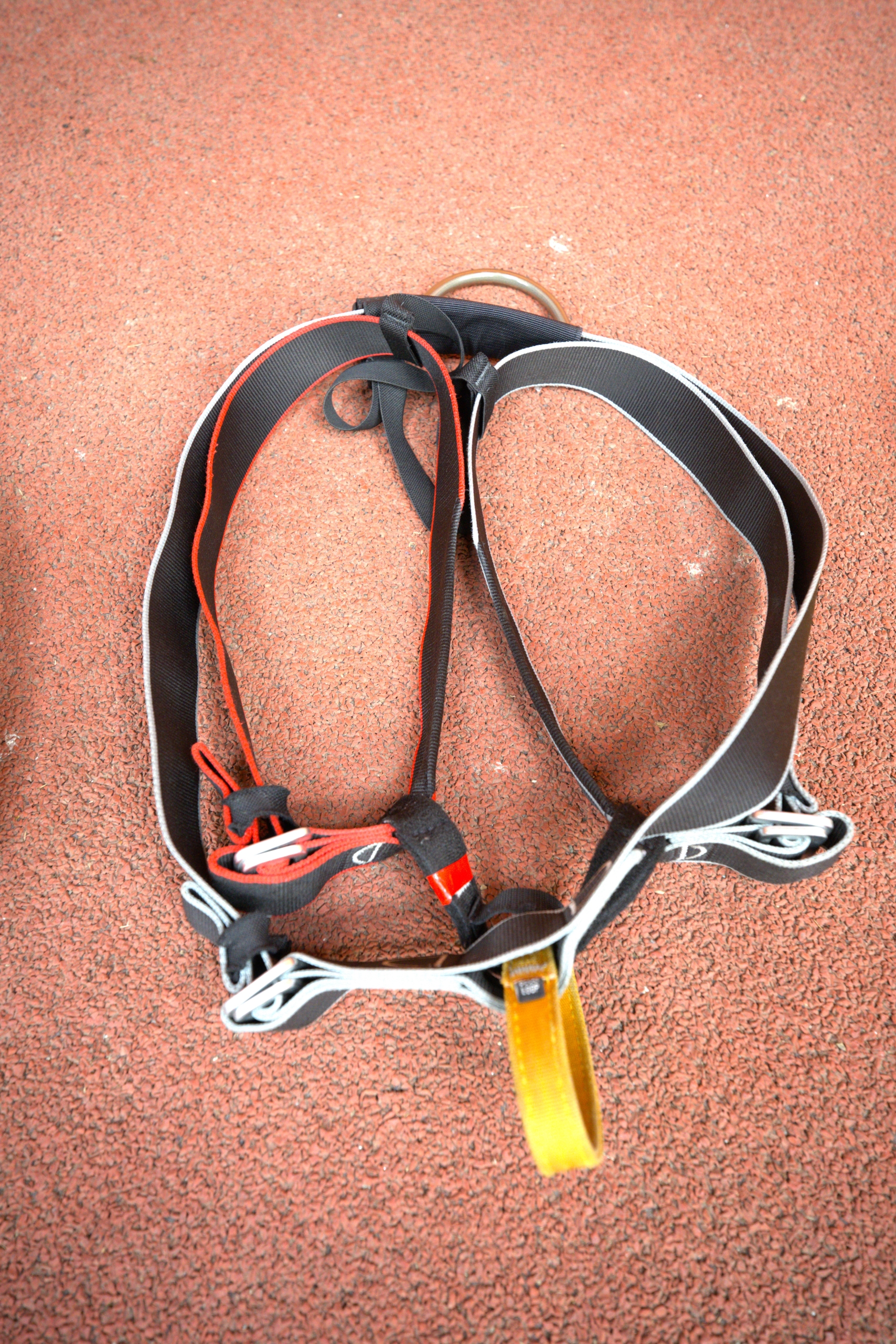 A red, white, black and yellow harness lying on the floor ready to put on.