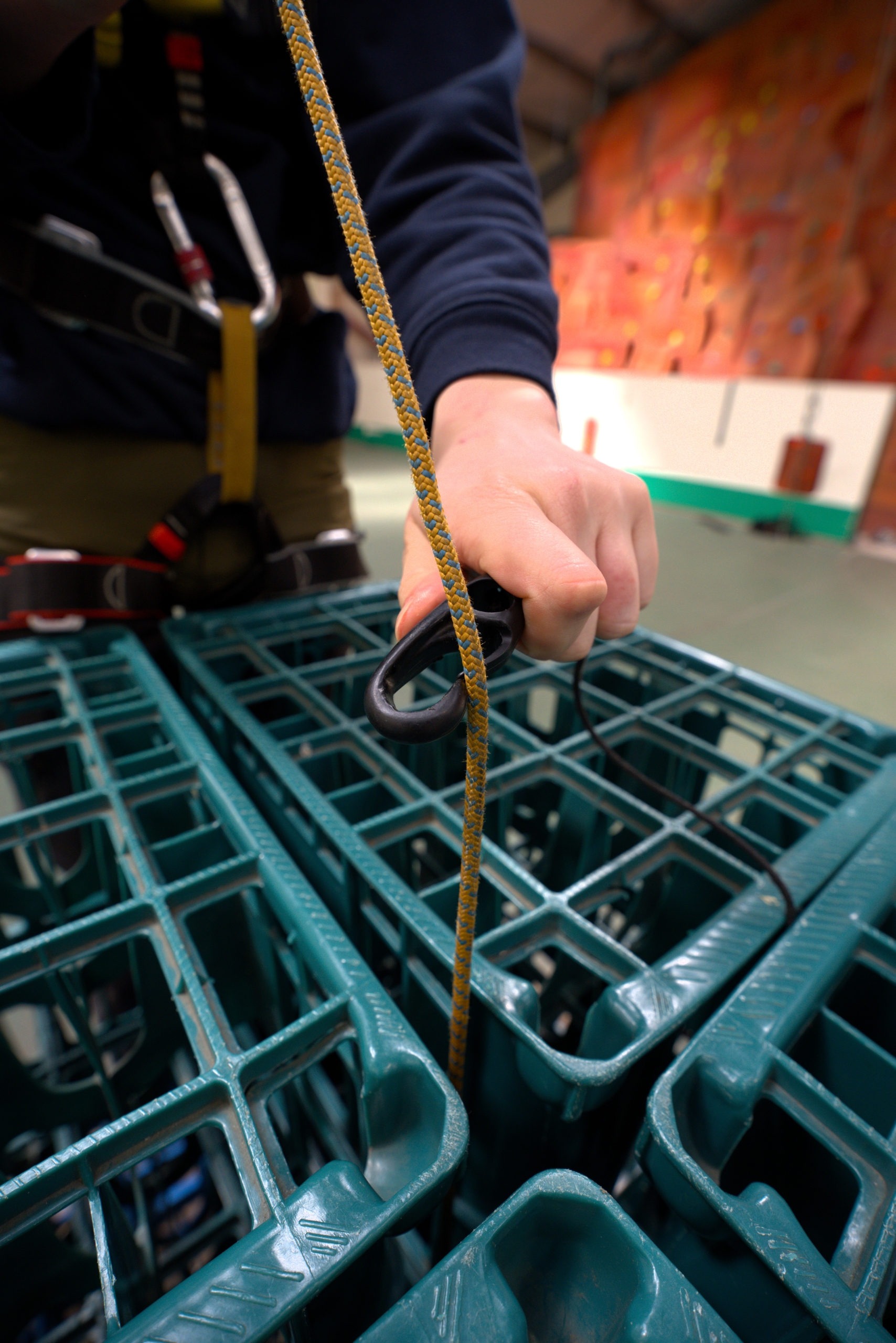 The foreground shows plastic milk crates, with a rope extending out from the middle of them, where someone's hand is clipping a black clip onto the rope.