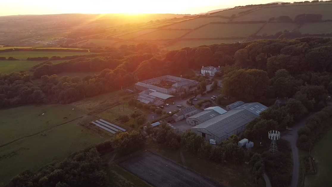 An aerial image of Calvert Exmoor's site, with the sun setting behind the hills in the distance.