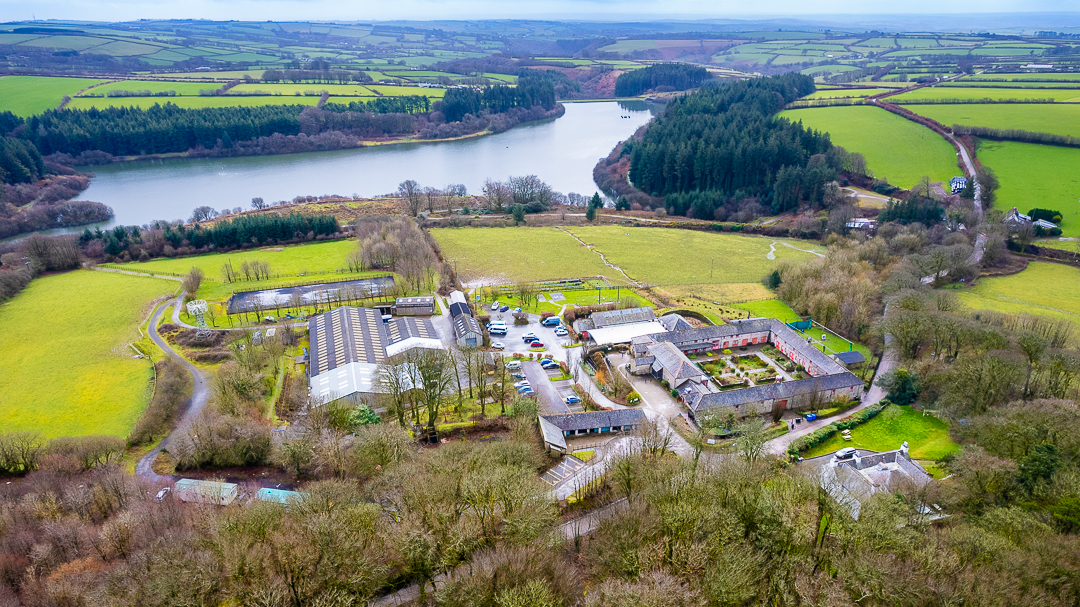 A birds eye aerial view of the Calvert Exmoor grounds, with Wistlandpound Reservoir in the background and Exmoor hills in the distance.
