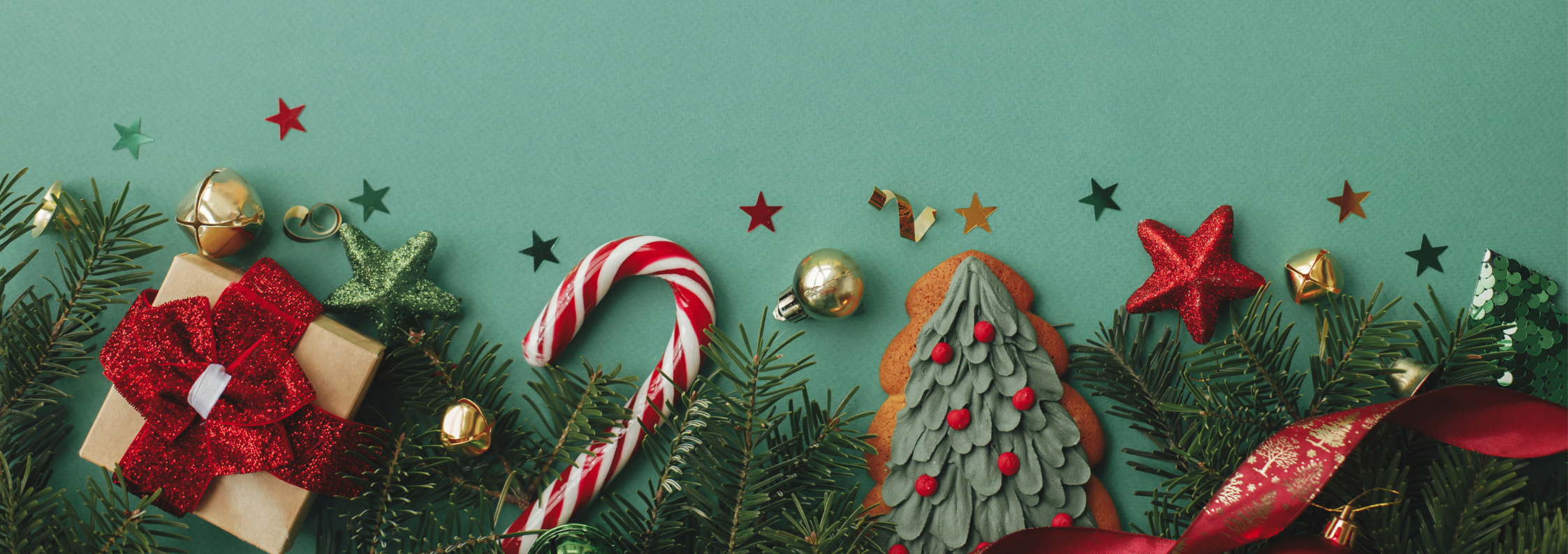 A selection of Christmas and festive items like presents, tree cookies and candy canes on a green background