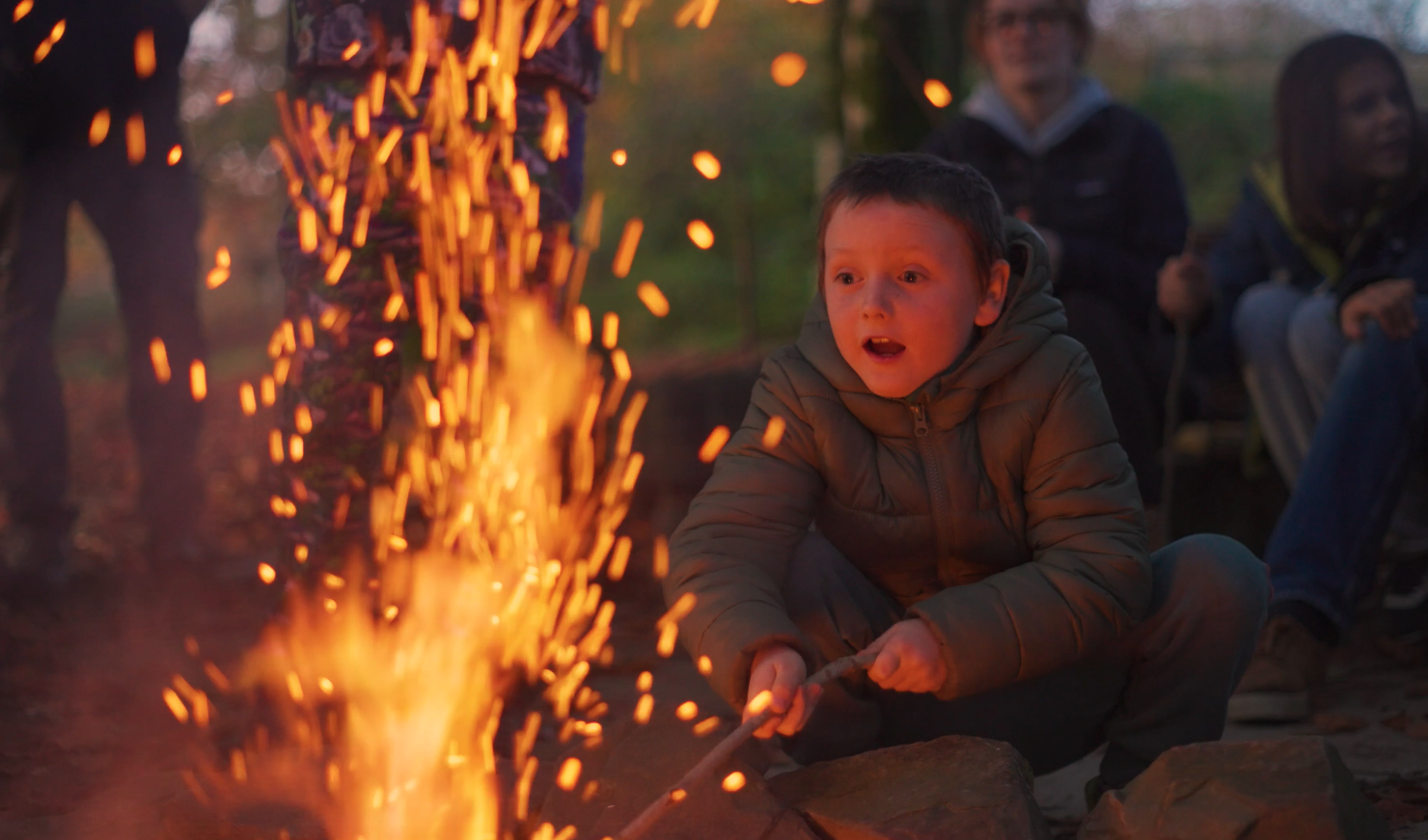 A child looks in awe at sparks coming out of a bonfire