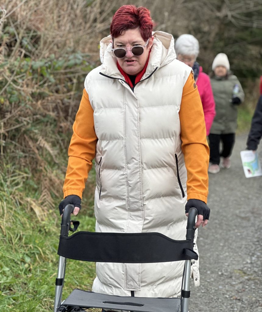 A lady walking through the countryside towards the camera with a frame